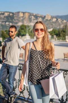 Shopping. Happy young couple with shopping bags in the city of Valence (France) with ruins of Crussol in the background.