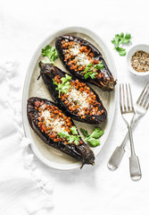 Stuffed lentils roasted eggplant - delicious healthy vegetarian served lunch  table. On a light background, top view