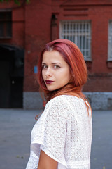 Fashion art photo. Portrait of sexy woman with long red hair, in the city.