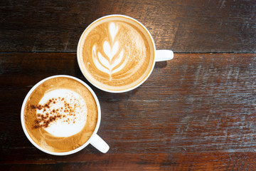 Cup of hot cappuccino and latte art coffee on wooden table in the coffee shop, top view