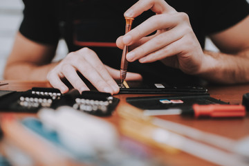 Fototapeta premium Close up Young Man Repairing Mobile Phone at Table