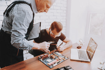 Two Men Repairing Hardware Equipment in Workshop.