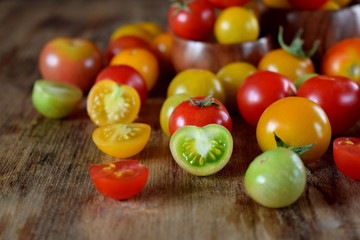 Assortment of multicoloured whole and cut tomatoes on a wooden table