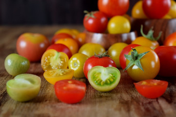 Assortment of multicoloured whole and cut tomatoes on a wooden table