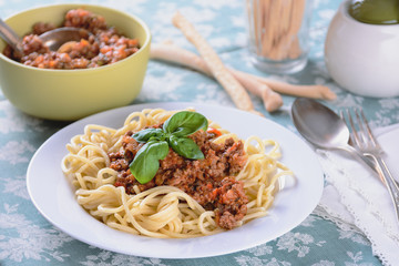 Spaggettes with bolognese sauce in a white plate are on the dining table