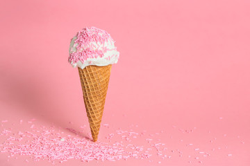 funny creative concept of wafer cone with ice cream covered and strewed sprinkles on pink...