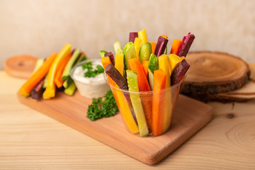 colorful carrots and cucumbers vegetables julienned with sour cream dip on wooden cutting board, concept healthy lifestyle