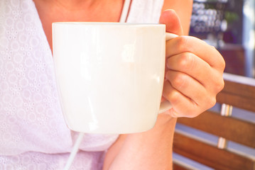 Woman with white cup of coffee in hand.