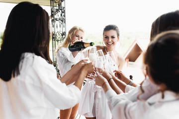 Happy bride and bridesmaids drink champagne on the balcony