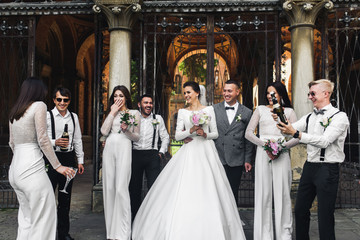 Group portrait of newlyweds and their friends having fun on the backyard