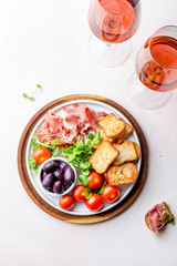 Antipasto Plate with dried bread, ham serrano, tomato cherry and purple olives. White background.