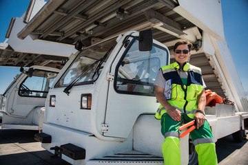 Resting from work. Cheerful man in sunglasses holding signal wands while sitting on truck