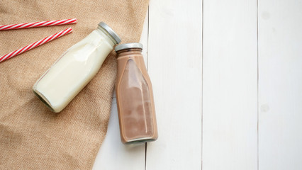 Milk and chocolate milk on a white wooden table.