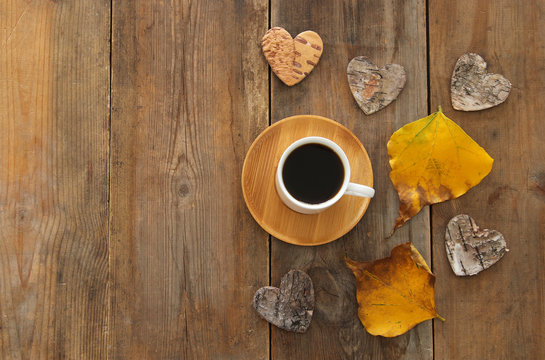 top view image of coffee cup over wooden table and dry autumn leaves.
