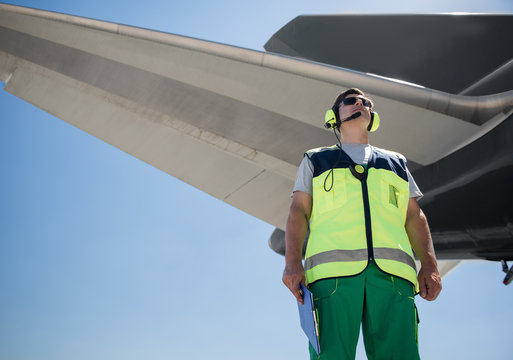 Beautiful view. Low angle portrait of airport worker. Man holding clipboard and looking up with calmness