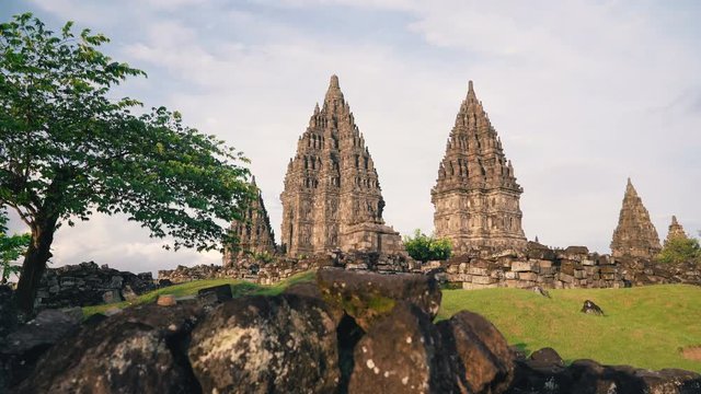 Prambanan temple and green lawn and tree in Jogjakarta, Indonesia on sunny evening, slide right