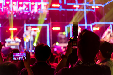 Crowd of hands up concert stage lights enjoying concert, and people fan audience silhouette raising hands in festival music rear view with spotlight glowing effect, blurred