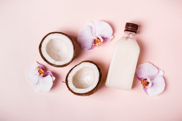 Obraz na płótnie Canvas Coconut oil and halves of fresh coconut on a pink background. Hair care spa concept. Toned