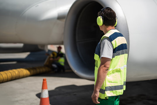 Keep working. Back view of ground crew member near commercial jet. Partner preparing aircraft for flight