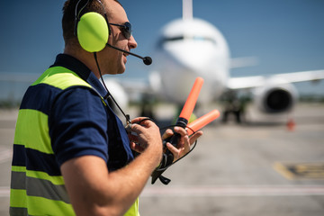 Important conversation. Side view of aviation marshaller talking on portable radio