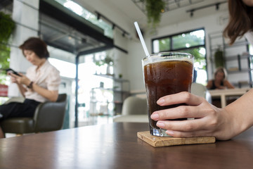 Close up woman hand holding ice black coffee in coffee shop
