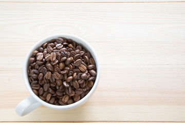 A coffee cup full with coffee beans on wooden background