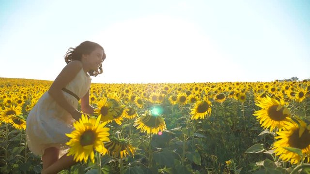 Happy little girl running happy free across the field with sunflowers. slow motion lifestyle video . smelling big sunflower on summer field. Delight of a pleasant smell. Summer holiday. concept