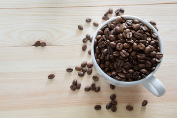 A coffee cup full with coffee beans on wooden background