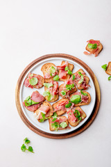 Mini open sandwiches with jamon serrano on white plate