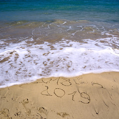 New Year 2019 is coming concept - inscription 2018 and 2019 on a beach sand, the wave is starting to cover the digits 2018