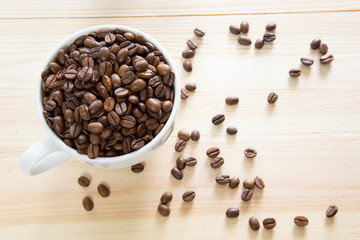 A coffee cup full with coffee beans on wooden background