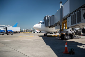 Waiting for the takeoff. Side view of commercial jet loading up luggage. Airport, blue sky, truck and trolleys on background