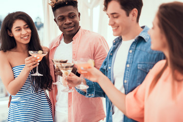 Cheerful women and smiling men tasting appetizing beverage while speaking together