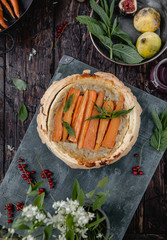 elevated view of cooked yummy pie with carrots and herbs on wooden table