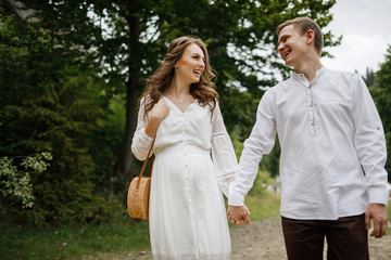 Happy pregnant family having fun time in summer nature. 