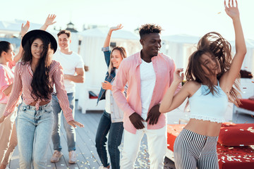 Cheerful ladies and beaming males gesticulating hands while dancing during party. Glad friends during entertainment concept - obrazy, fototapety, plakaty