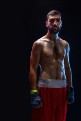 Fototapeta na wymiar Young male boxer wearing his red boxing shorts and bandage on black background