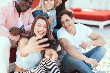 Beaming girl and happy men looking at display of modern phone while taking photo on appliance