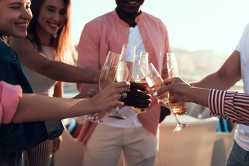 Cheerful girls and beaming men drinking alcohol liquid while locating outdoor during party