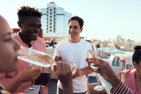 Positive male communicating with cheerful women while tasting delicious beverage outside