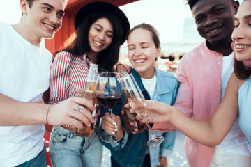 Outgoing ladies and cheerful males drinking alcohol beverage while talking together