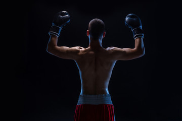 Back view of man boxer with raised hands in victory gesture. Concept of hard sport, glory and...