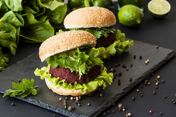 Two vegan burgers with beet cutlet on black background. Healthy fastfood. Vegan food.