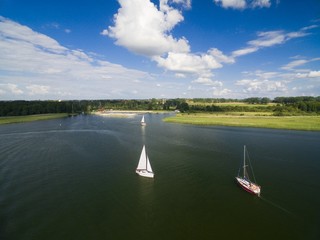 Aerial view of yachts sailing on Mamry Lake, concrete quay and town beach in the background, Wegorzewo, Mazury, Poland