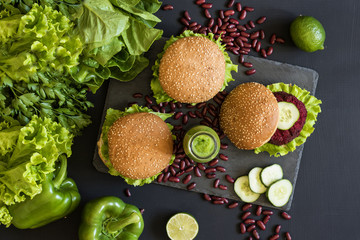 Vegan burgers with beet cutlet and green smoothies on black background. Healthy vegan food. Detox diet. Flat lay.