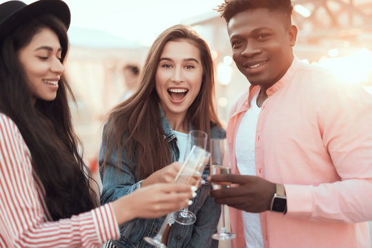 Portrait of happy man and cheerful females enjoying glasses of champagne during party