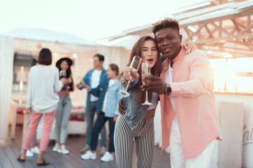 Portrait of beaming lady and happy man hugging while drinking glasses of champagne