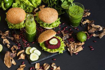 Vegan burgers with beet cutlet and green smoothies on black background. Healthy vegan food. Detox diet.