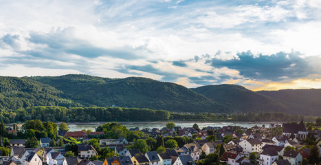 Fototapeta na wymiar Beautiful green hills on the banks of the Rhine river on a cloudy summer sunset in western Germany. Panorama in high resolution.