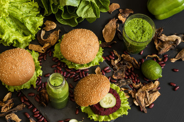 Fototapeta na wymiar Vegan burgers with beet cutlet and green smoothies on black background. Healthy vegan food. Detox diet.